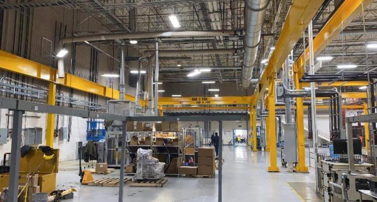 Técnicos instalando grúa aérea en planta industrial